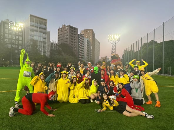 A large group wearing colorful costumes on an outdoor sports field